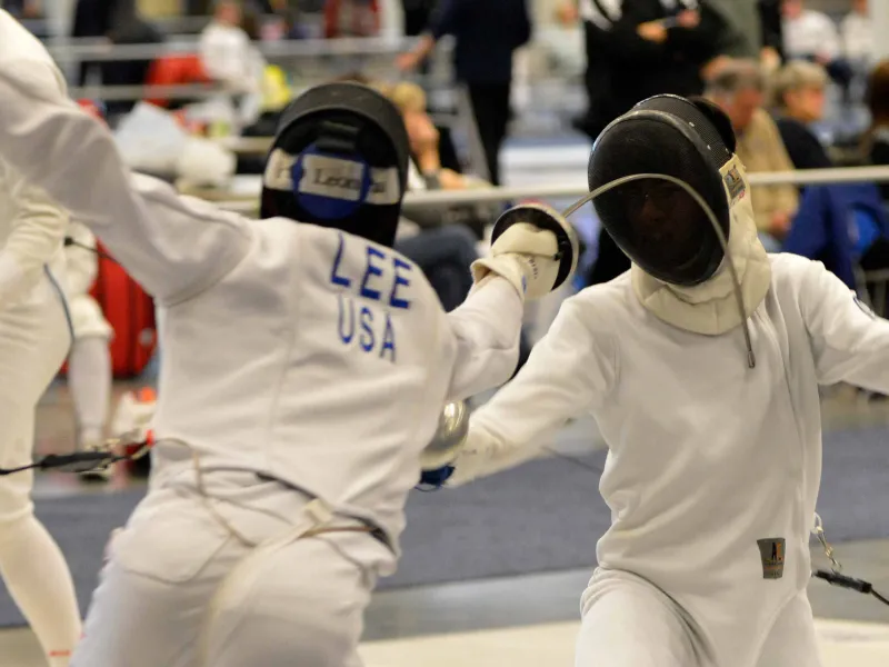 Two MTFC fencers mid-bout on the foil strip